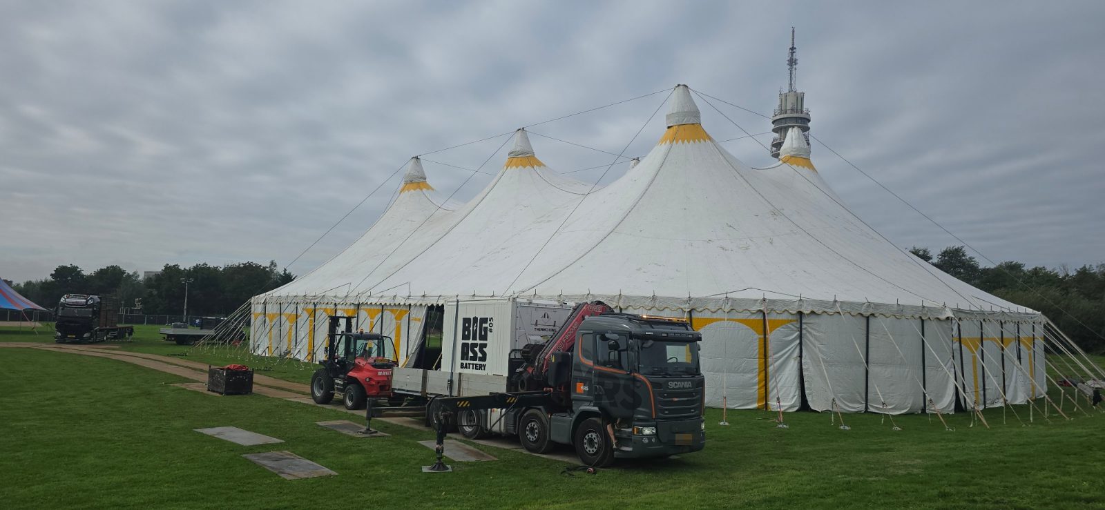 Grote festivaltent tijdens de opbouw, met een kraanwagen en een accucontainer ervoor